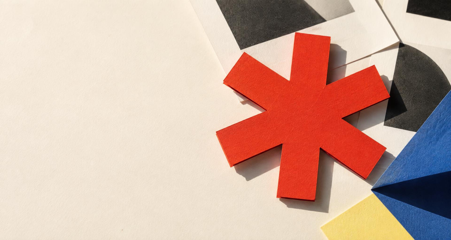 Roter Papierstern zwischen grafischen Druckbögen und farbigen Papieren